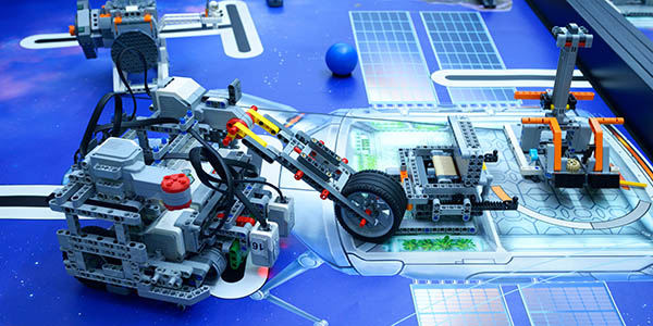 Custom Lego robots set up on a competition mat with space-themed obstacles.